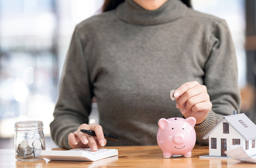 A Woman putting money into a piggy bank to save for a future purchase.