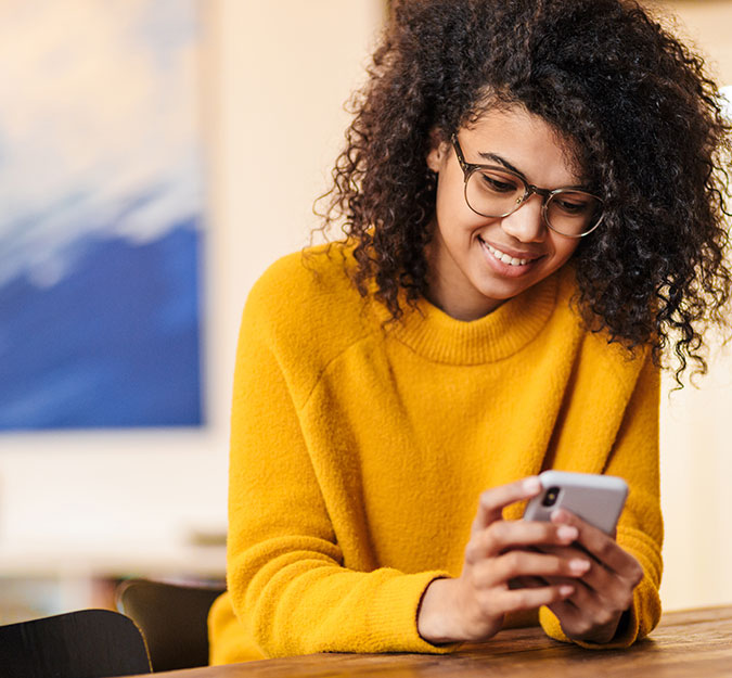 A young adult checking their KVSB Mobile Banking at a coffee shop.
